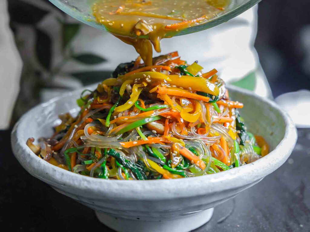 adding broth to vegetarian japchae